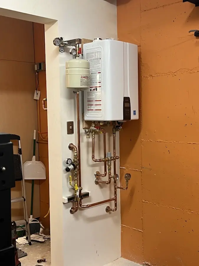 Plumbing technician inspecting water heater connections in New Castle
